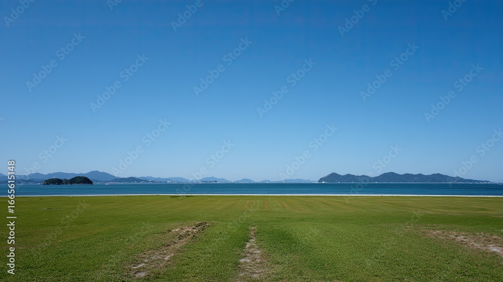 Fototapeta premium Large green meadow with small islands in foreground and clear blue sea view under cloudless sky. Green space management landscape for lawn care product advertisement.