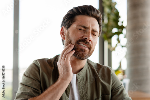 Photos Man suffering from strong toothache touching his cheek