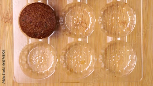 Pastry chef takes mini chocolate cupcake from blister pack on wooden board