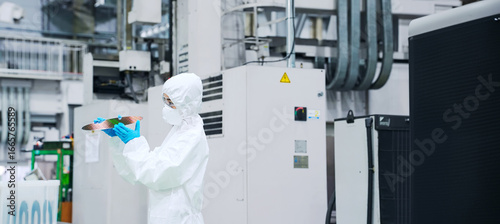 Tableau sur toile A female worker in a dustproof suit inspecting silicon wafers in a semiconductor