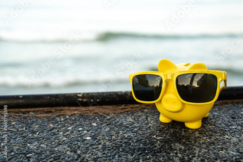 Vacation savings concept with piggy bank wearing sunglasses and beach umbrella. Piggy bank on vacation