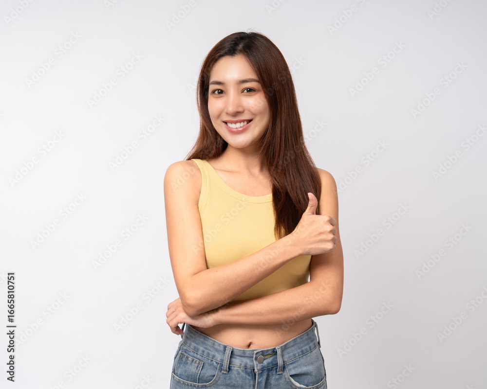 Fototapeta premium Beautiful smiling happy young asian woman in yellow shirt showing thumbs up. Charming female lady standing pose on isolated white background. Asian woman people looking camera confident