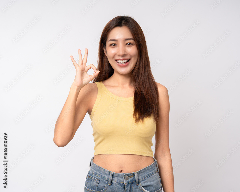 Beautiful smiling happy young asian woman in yellow shirt showing ok sign. Charming female lady standing pose on isolated white background. Asian woman people looking camera confident Beautiful smiling happy young asian woman in yellow shirt showing ok sign. Charming female lady standing pose on isolated white background. Asian woman people looking camera confident