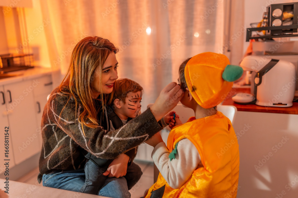 Obraz premium Mother applying halloween makeup on children at home