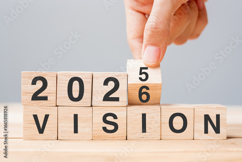 hand flipping block 2025 to 2026 VISION text on table. Resolution, strategy, goal, motivation, reboot, business and New Year holiday concepts