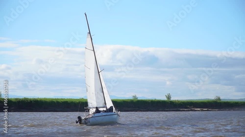 Sailboats are sailing on a lake. The sailboat is white . The sky is cloudy