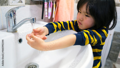 Quadro su tela A young girl washes her hands in the sink