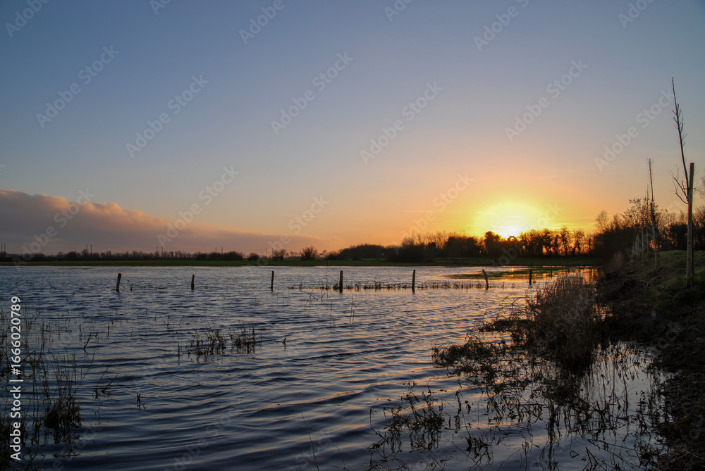 Fototapeta premium Body of water with a sunset in the background