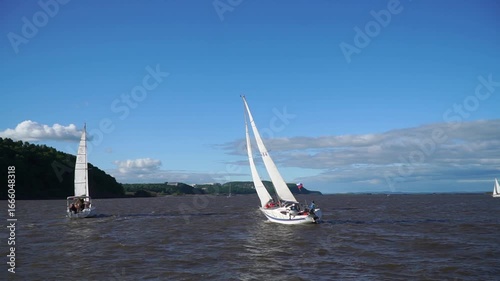 Sailboats are sailing on a lake. The sailboat is white . The sky is cloudy
