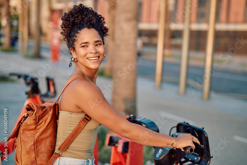 Young tourist is smiling while renting an electric scooter in the city center using a smartphone app
