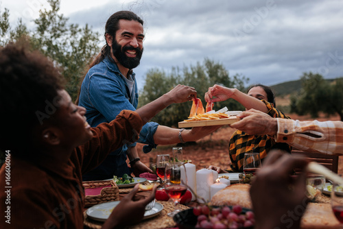 Fotografie Friends sharing appetizers at outdoor dinner party in olive grove