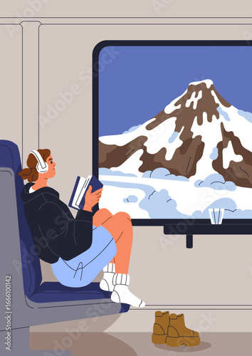 Travel by train. Young female tourist in headphones, reading book and looking...