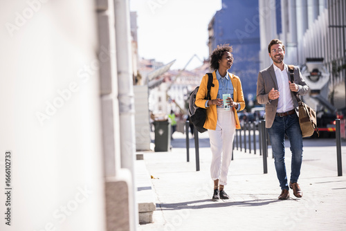 Business colleagues walking and conversing outdoors in urban city