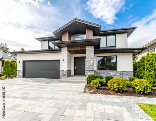 A modern two-story house with a combination of white, wood, and dark gray exterior, featuring a paved driveway and landscaping.