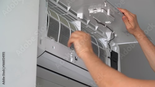 Air conditioning maintenance. Hands of repairman change cleaning filter in air conditioner. Purification and repair of cooling system