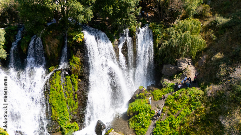 Fototapeta premium Aerial view of a beautiful waterfall cascading down rocky cliffs