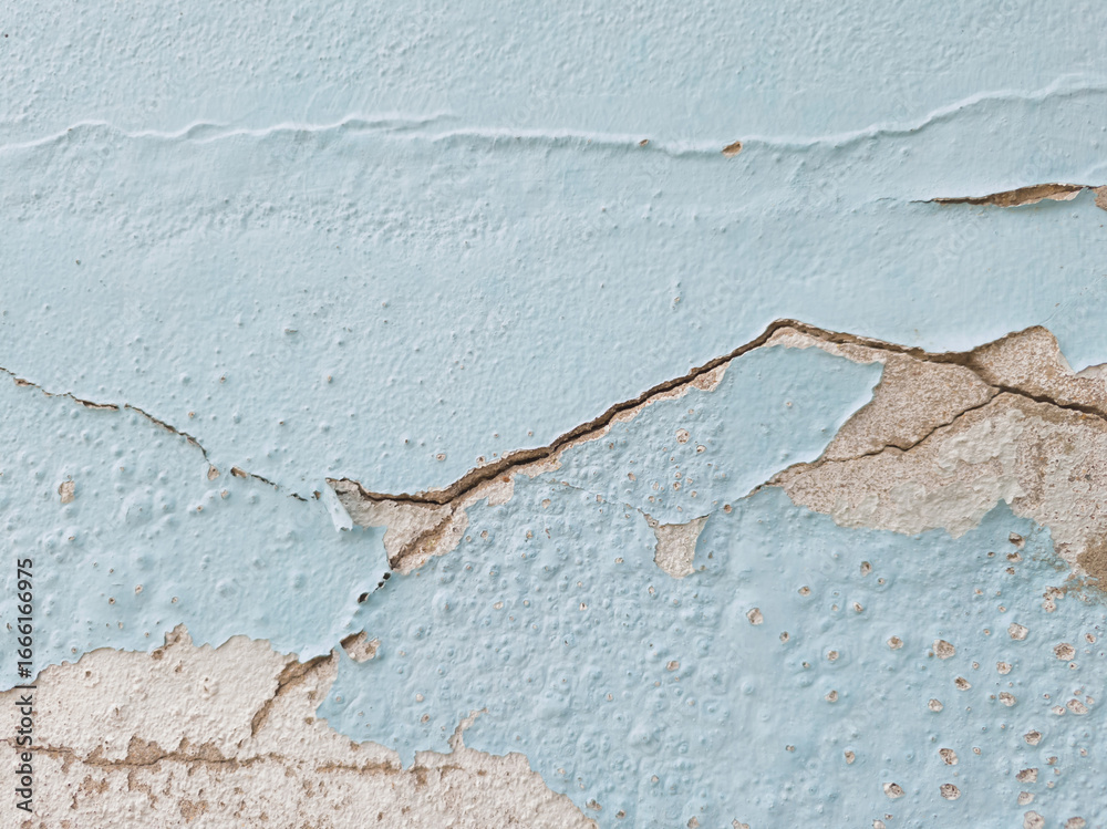 Obraz premium Close-up light blue painted wall with large, peeling sections revealing gray, rough concrete underneath. Old paint is flaking and cracked