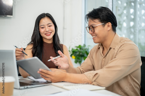 Businesswoman or office worker looking and pointing at tablet holding in man's hand at working table