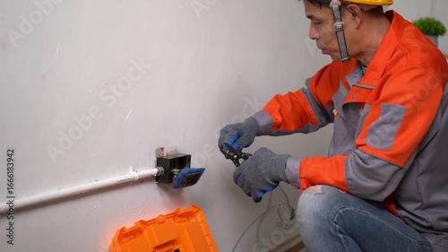 Experienced electrician wearing a hard hat repairing electrical wiring in a residential setting using tools and equipment for safety and precision