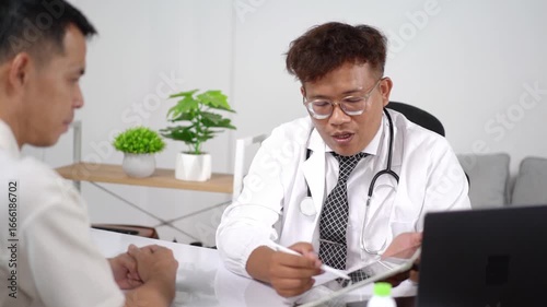 Male doctor consults with patient in modern office setting, discussing health issues and treatment options using digital tablet and laptop