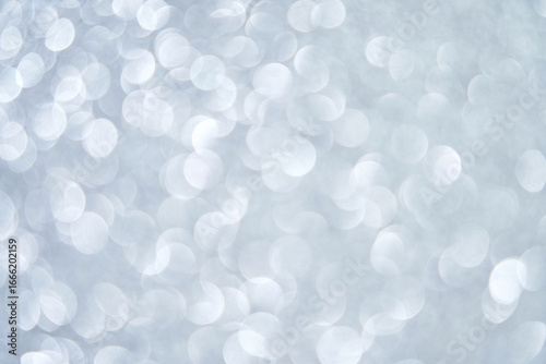 Abstract silver bokeh lights on soft gray background with circular blurred patterns.