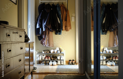 real life scene of a family, entrance part of the apartment, with outer clothes hanging and a shoes on a rack