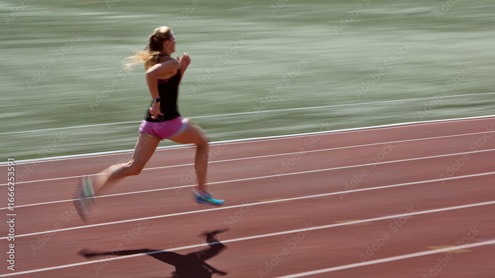 Obraz premium Female athlete sprinting on red track with blurred motion background, showing explosive stride and power. Concept of peak speed, athlete in motion, determination, and dynamic sprint action.