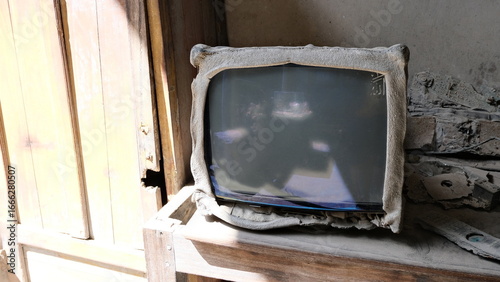An old television set covered in volcanic ash, damaged and abandoned in a house after Mount Merapi's eruption in Yogyakarta.  
