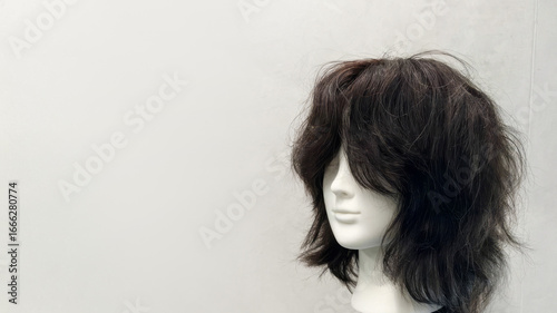 Fotografi A tousled black wig perched on a stark mannequin head whispers Halloween mystery