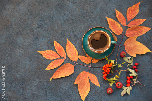 Autumn mood, a cup of coffee among autumn leaves on a wooden dark table with copy space. Top view.