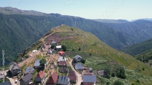 Aerial drone footage flying over traditional stone houses in Lukomir, the highest village in Bosnia and Herzegovina, located on mountain Bjelašnica. Scenic rural settlement with panoramic mountain lan