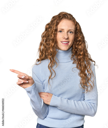 Simple redhead studio portrait smiling cheerfully pointing with forefinger away.