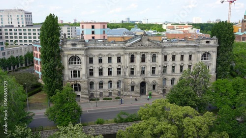 Berlin, Germany - May 31, 2025: Aerial view of a historic social science research building in Berlin, featuring classical architecture, lush trees, walking people and traffic.