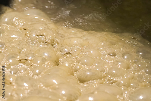 Foto Bubbles of foam in the dirty water of gold ore tank.