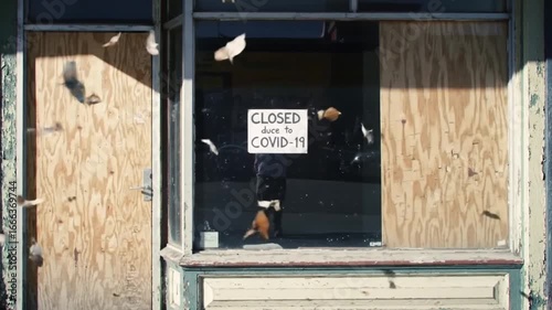 A storefront is boarded up with plywood, covering the and door, with a sign indicating the business is currently closed, possibly due to unforeseen circumstances.
