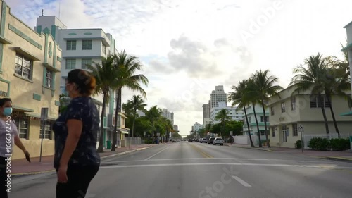 An expansive street scene unfolds, showcasing buildings of varying heights and architectural styles, with palm trees lining the sides and a cloudy sky overhead, creating a serene atmosphere.