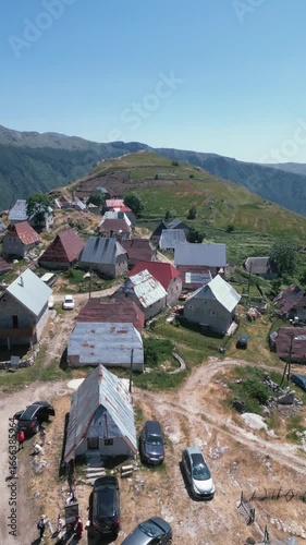 Aerial drone footage flying over traditional stone houses in Lukomir, the highest village in Bosnia and Herzegovina, located on mountain Bjelašnica. Scenic rural settlement with panoramic mountain lan