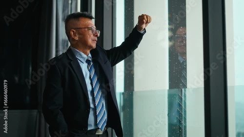 Asian businessman looks out window on modern tower,stressed about the economy,falling stocks,business crisis,uncertain future,financial failure,Bankruptcy.financial losses and Economic crisis concept