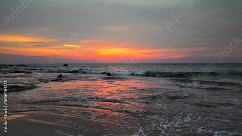Coastal Sunset Serenity The image captures a breathtaking sunset over the ocean, with the radiant colors of the sun reflecting on the water's surface and the shoreline.