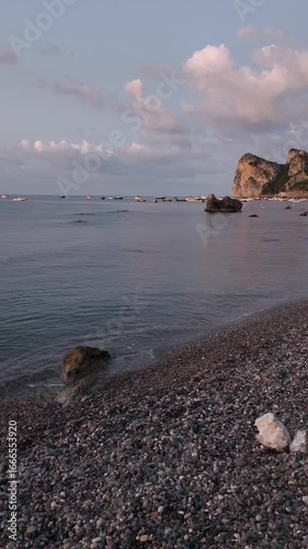 A romantic sunrise at Marina del Cantone, Amalfi Coast, Italy. The first light of day illuminates the small waves crashing gently on the beach, creating a dreamy and peaceful atmosphere on the Mediter