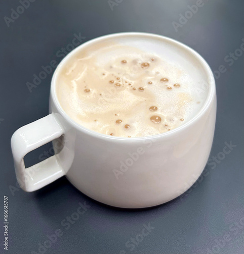 Large white cup of latte cappuccino coffee with thick foam on table on grey background
