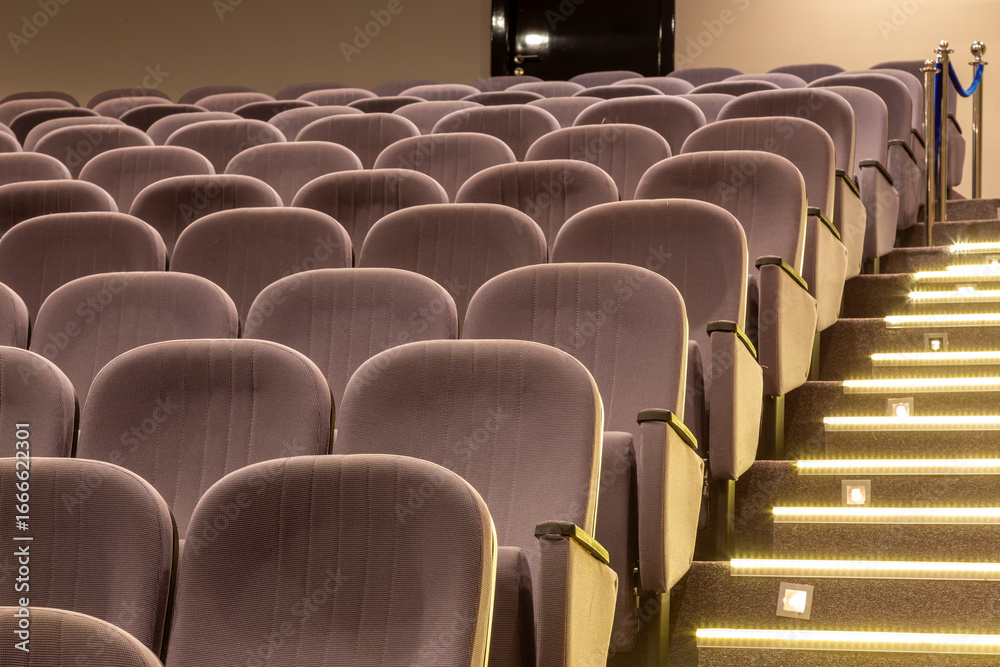 Fototapeta premium Empty seats in a modern theater or cinema auditorium. Rows of comfortable chairs awaiting the audience for a show, movie premiere, or conference.