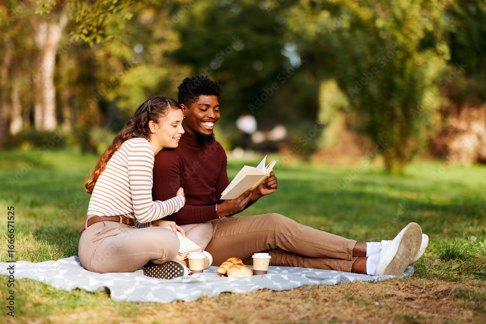 Happy multi-ethnic couple enjoying a book and picnic in autumn park Happy multi-ethnic couple enjoying a book and picnic in autumn park