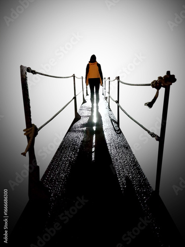 Into the unknown...a woman walks tentatively across a bridge into a bright light