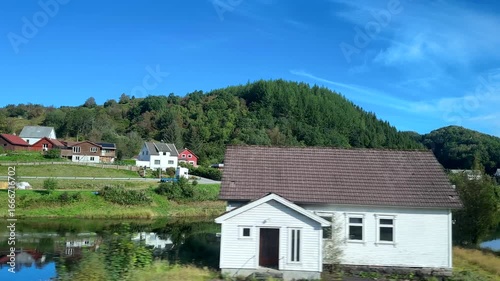 Wallpaper Mural Amazing views of Norway through bus side window on a sunny day. Colourful village houses, blue sky and green forest mirror reflection on lake or river surface. Torontodigital.ca