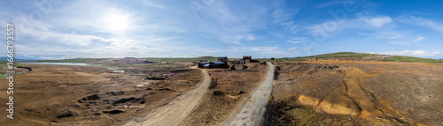 Fotografie Expansive panoramic aerial view showcases the remnants of an abandoned copper mine in Røros, Norway, characterized by desolate terrain and industrial relics under a clear sky