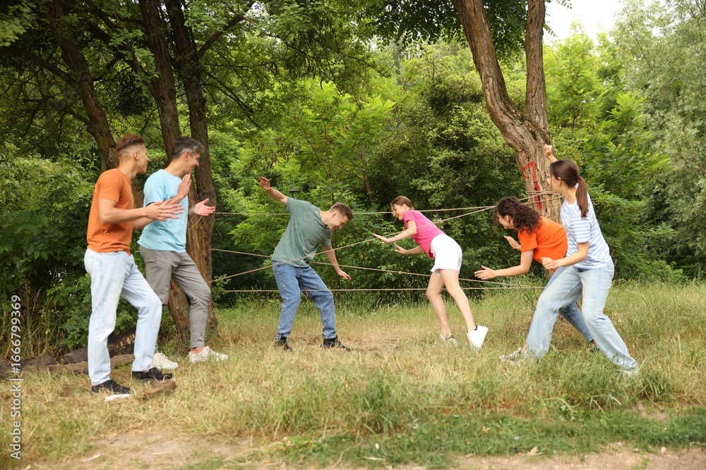 Fototapeta premium Team building. Group of happy people playing spider web game outdoors