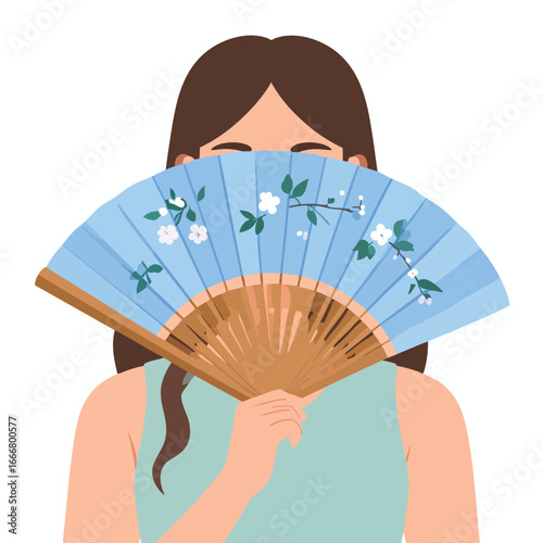 A woman holding a blue, floral-decorated fan in front of her face.