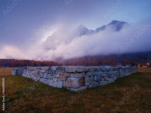Mountain landscape at dawn. Sunbeams in a valley. Foggy weather in the mounta...