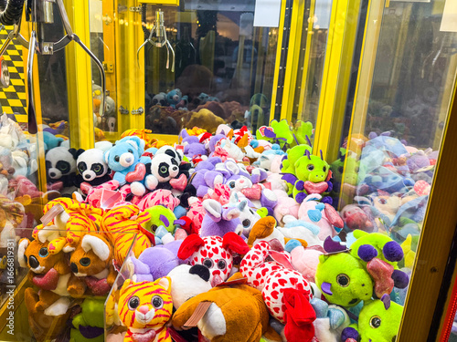 Claw machine filled with colorful stuffed animals and toys. Entertainment, leisure, childhood and amusement in an indoor arcade setting.